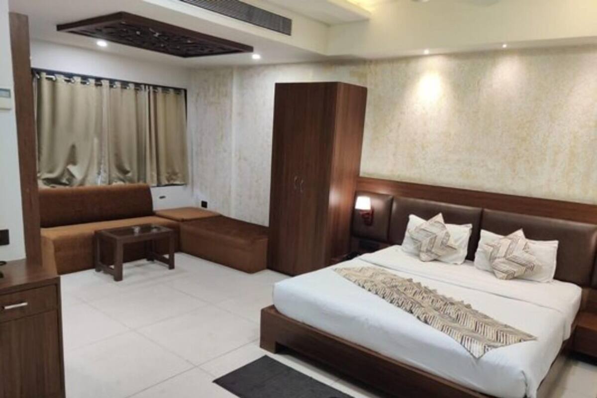 Une chambre d’hôtel moderne avec un grand lit, un canapé, une petite table et une armoire.