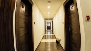Ein Hotelgang mit Holztüren, einem Schachbrettfußboden und einem Rauchmelder an der rechten Wand.