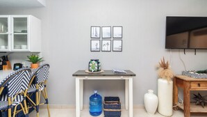 A modern living room with a dining area, a TV mounted on the wall, and a large water dispenser.