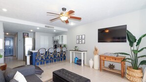 A modern living room with a sofa, ottoman, and a dining area with chairs and a table.