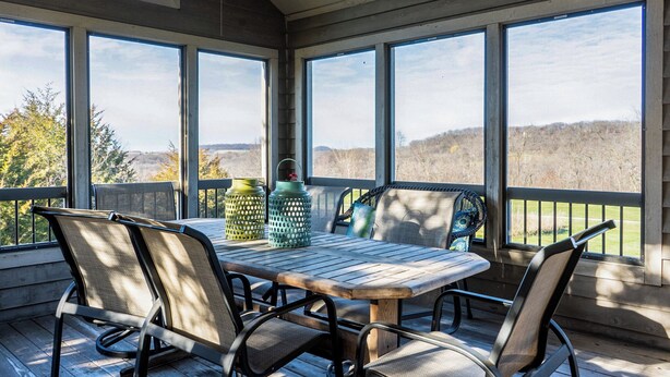 A covered patio with a wooden table and chairs, large windows, and a view of a hilly landscape. - 3 Bedroom, 3 1/2 bath house in The Galena Territory. (Galena)