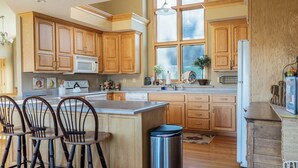 A spacious kitchen with wooden cabinets, a central island with bar stools, a stainless steel trash can, and a large window providing natural light. - 3 Bedroom, 3 1/2 bath house in The Galena Territory. (Galena)