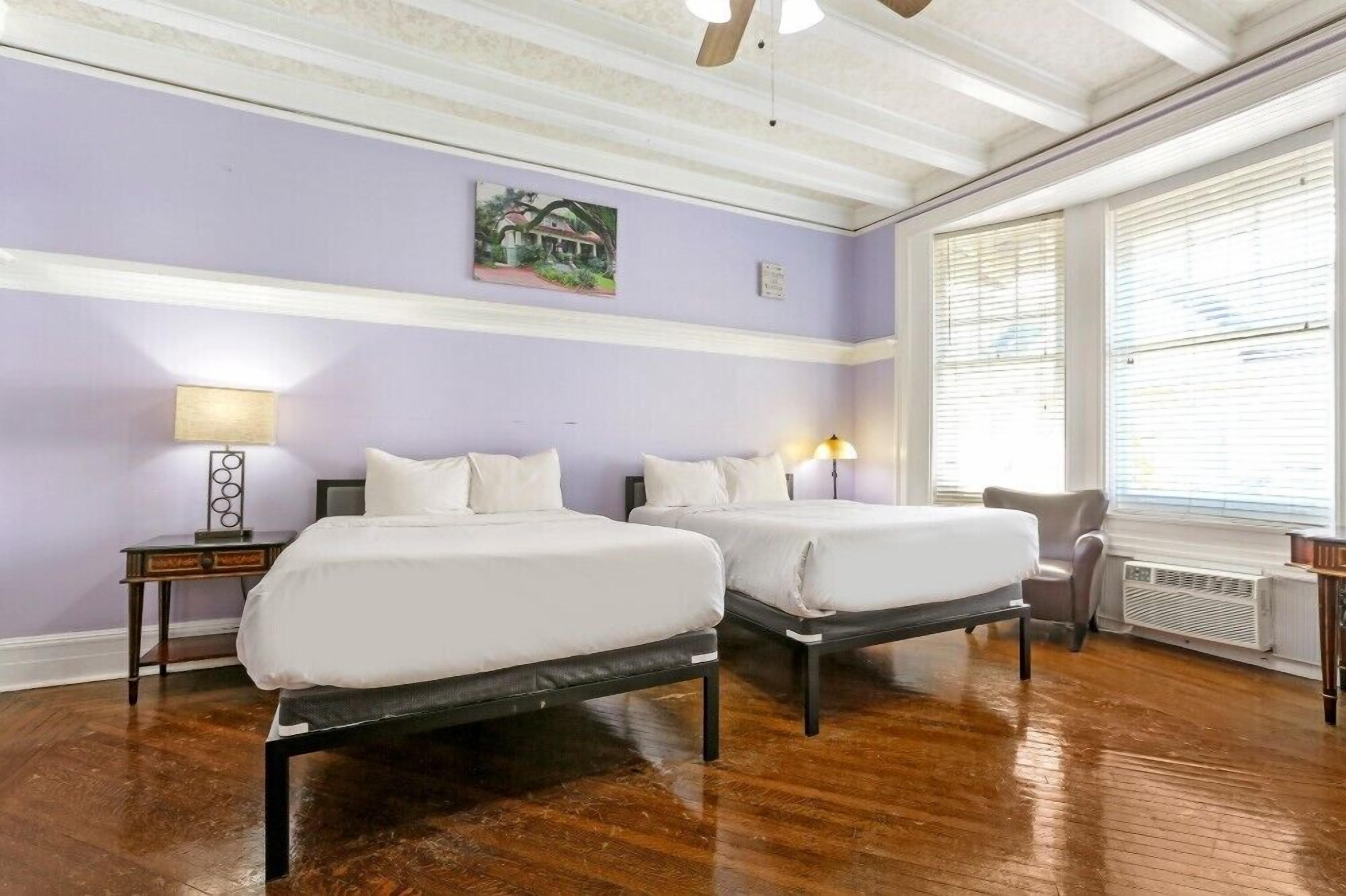 Una habitación con dos camas, una silla, una mesa y una ventana con persianas.