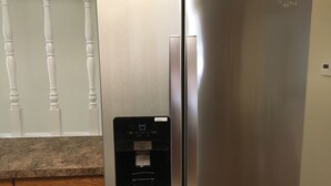 Un réfrigérateur Whirlpool en acier inoxydable, doté d’un distributeur d’eau et d’un compartiment congélateur.