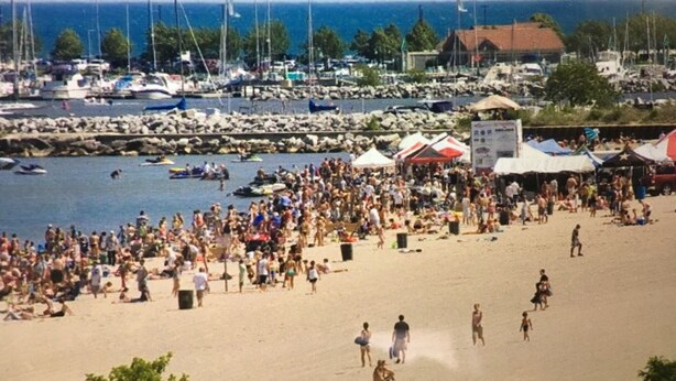 Une plage bondée, avec des gens, des bateaux et des tentes.