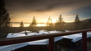 A view from a balcony with snow-covered tables and chairs, overlooking a lake and trees during sunset. - Sleep 6 With Stunning Views Of Lake Tahoe  (Incline Village)