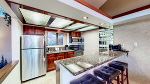 A modern kitchen with granite countertops, stainless steel appliances, and a bar area with stools. - Sleep 6 With Stunning Views Of Lake Tahoe  (Incline Village)