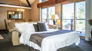 A bedroom with a large bed, a chandelier, a dining table, and a view of the outdoors. - Sleep 6 With Stunning Views Of Lake Tahoe  (Incline Village)