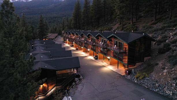 A row of log cabin-style lodges with a central walkway, surrounded by forested mountains. - Sleep 6 With Stunning Views Of Lake Tahoe  (Incline Village)