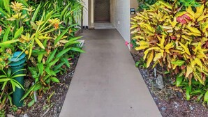 A multi-story building with a central staircase, surrounded by lush greenery and a concrete pathway. - Kona Condo- Family Friendly- Fall Sale! (Kailua-Kona)