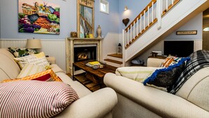 Ein Wohnzimmer mit Kamin, Treppe und einem Gemälde an der Wand.