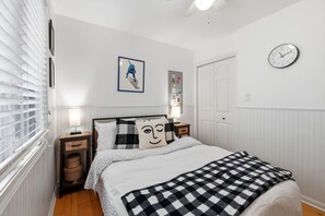 A bedroom with a bed, bedside lamps, a wall clock, a framed picture, and a door. - UNION PIER HOME WITH PRIVATE HOT TUB and CLOSE TO BEACH! 2023 Open! (Union Pier)