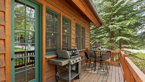 A wooden deck with a grill, outdoor seating, and a view of trees. - RMR: Granite Ridge Homestead 3132 in Teton Village (Teton Village)