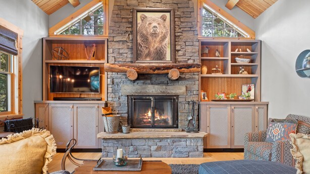 A cozy living room with a stone fireplace, wooden shelves, and a large bear painting above it. - RMR: Granite Ridge Homestead 3132 in Teton Village (Teton Village)