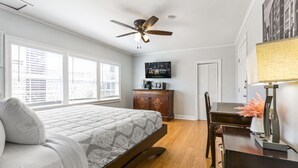 A bedroom with a bed, a ceiling fan, a desk, and a television on the wall. - Relaxed Studio | Festivals & Fun Nearby (New Orleans)