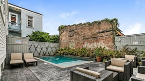 A backyard with a swimming pool, outdoor furniture, and a brick wall.