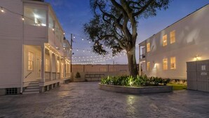 A courtyard with a tree, string lights, and a building with a porch.