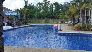 A backyard swimming pool with a wooden deck, lounge chairs, and a wooden fence. - Reunion Paradise! Spacious Luxury Home and Pool House (Virginia Beach)