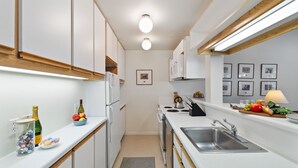 Une cuisine moderne avec des armoires blanches, un évier en acier inoxydable et un plan de travail en bois.