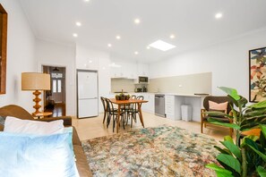 A compact hotel room with a bed, a dining table with chairs, a kitchen area with a refrigerator, microwave, and sink, and a large window. - Carlton Terrace Pet Friendly (Carlton)