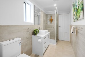 A modern bathroom with a toilet, sink, and shower. - Carlton Terrace Pet Friendly (Carlton)