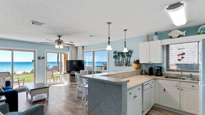 Una cocina moderna con una isla grande, armarios blancos y vista al océano.