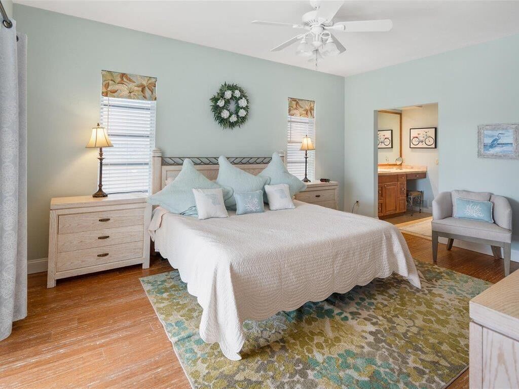 A bedroom with a bed, nightstands, a desk, and a chair.
