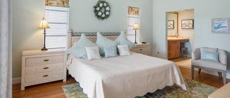 A bedroom with a bed, nightstands, a desk, and a chair.