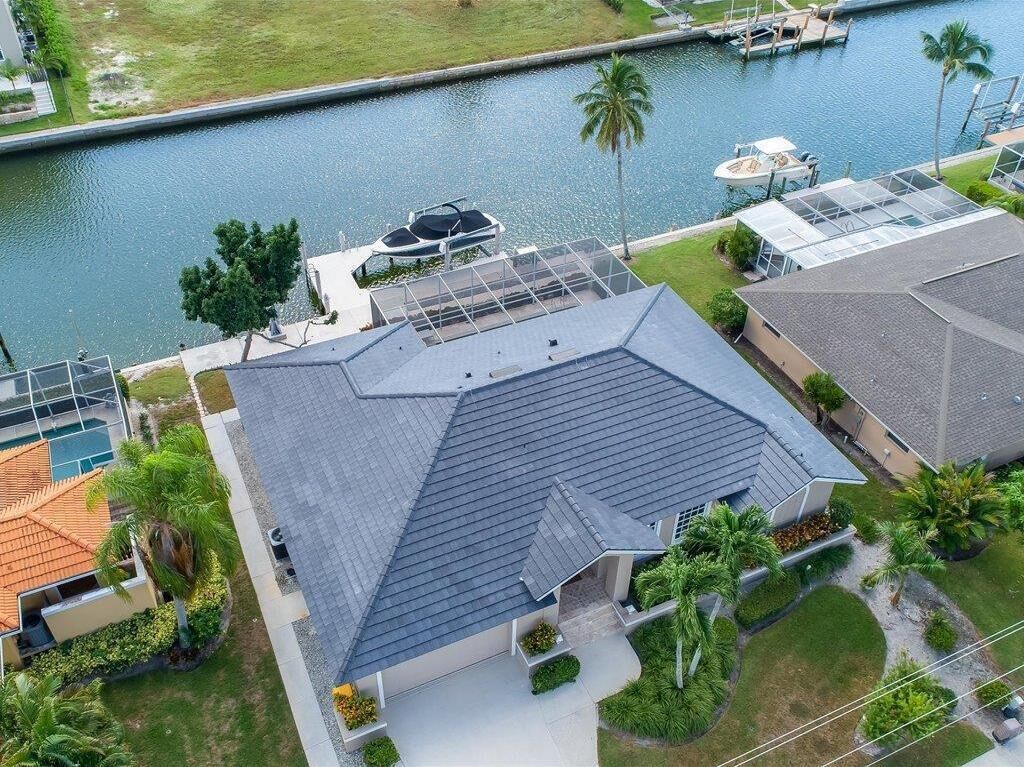 A residential property with a sloped roof, a swimming pool, and a dock by a body of water.