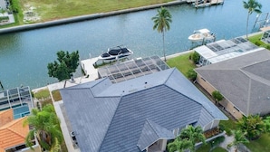 A residential property with a sloped roof, a swimming pool, and a dock by a body of water. - Waterfront 3BR home with heated pool in Marco Island. (Marco Island)