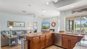 A modern kitchen with wooden cabinets, a granite countertop, and a built-in dishwasher. - Waterfront 3BR home with heated pool in Marco Island. (Marco Island)