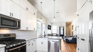 A modern kitchen with white cabinetry, stainless steel appliances, and a central island. - Spacious Condo w/ Pool & Courtyard Near French Quarter (New Orleans)