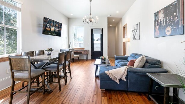 A spacious living room with a dining area, a blue sofa, and a chandelier. - Spacious Condo w/ Pool & Courtyard Near French Quarter (New Orleans)