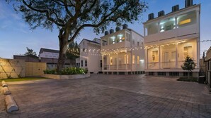 A two-story house with a covered porch and string lights. - Spacious Condo w/ Pool & Courtyard Near French Quarter (New Orleans)