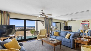 Un salón espacioso con televisor grande, asientos cómodos y vistas a la playa.