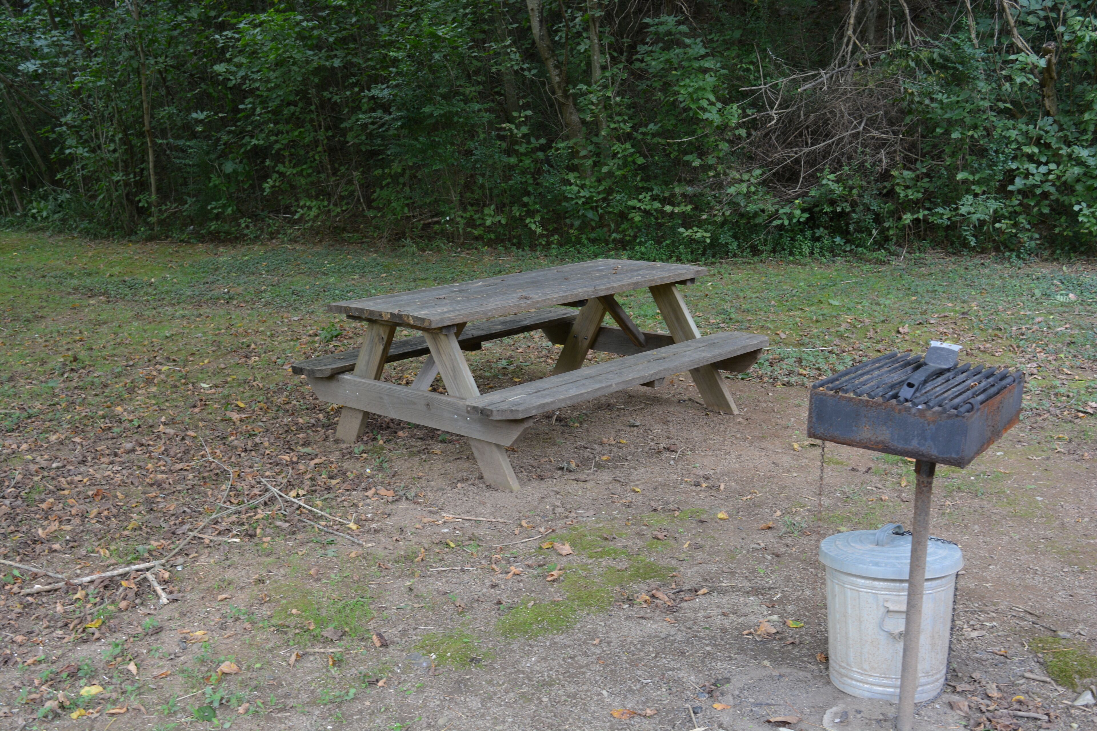 Une table de pique-nique en bois avec des bancs, un seau en métal et une boîte à outils contenant divers outils.