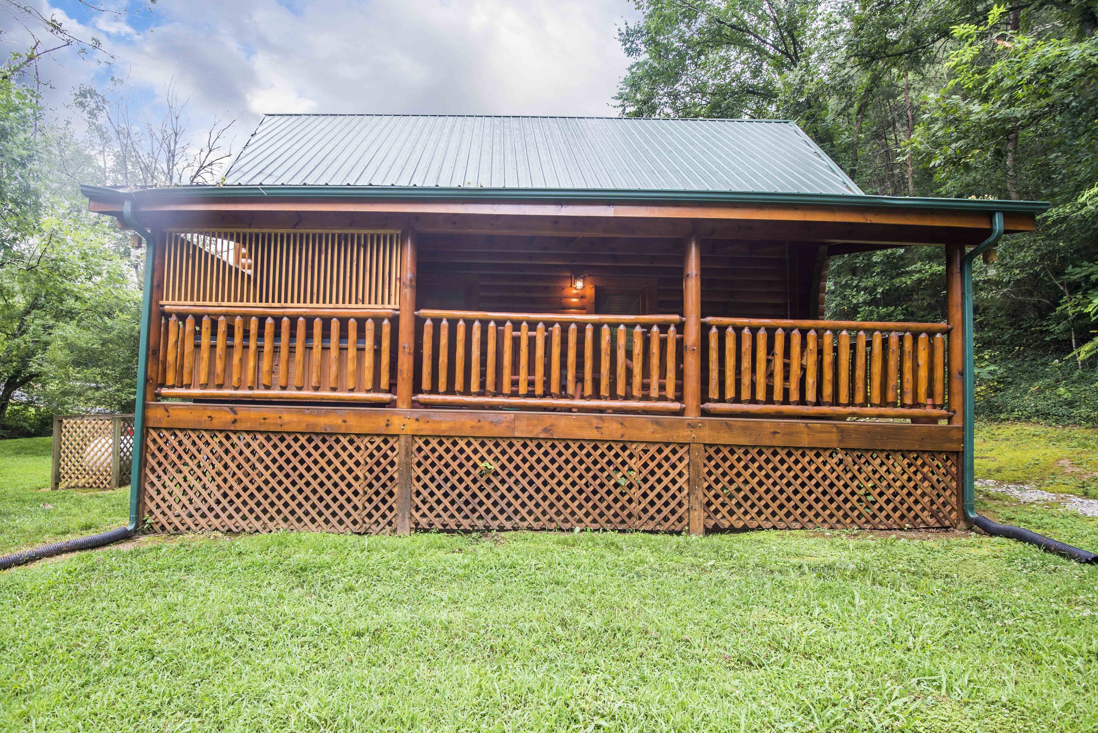 Une cabane en bois dotée d’un balcon, entourée d’une clôture en bois et agrémentée d’un panneau ajouré.