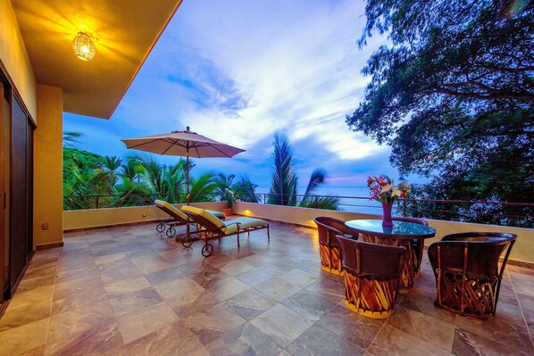 A terrace with a dining area, lounge chairs, and a table with chairs.