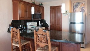 A kitchen with wooden cabinets, a stainless steel refrigerator, a microwave, and a stove.