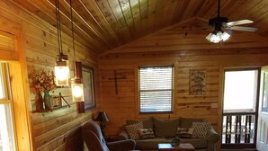 A cozy cabin interior with a wooden ceiling, a dining table with chairs, a sofa, and a ceiling fan. - SUNDANCER CABIN CADDO RIVER!!!!!   GREAT GETAWAY !!!!!!!! River Access!! (Glenwood)