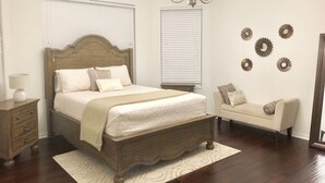 A bedroom with a wooden bed, bedside tables, a nightstand, a sofa, and decorative wall mirrors. - Spacious Modern Retreat for Family Fun Near Tampa! (Riverview)