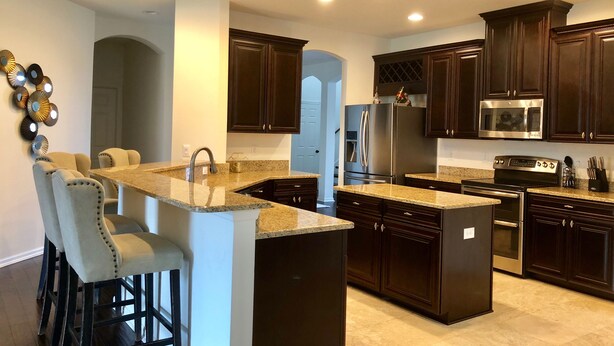 A modern kitchen with dark wood cabinets, stainless steel appliances, and a granite countertop. - Spacious Modern Retreat for Family Fun Near Tampa! (Riverview)