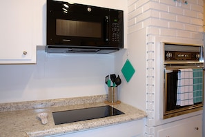 Kitchen area with microwave, stainless steel sink, and range hood.