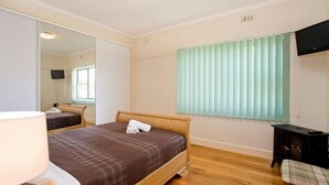A hotel room with a bed, a mirror, a television, and a window with blinds. - Bella Vista - Apollo Bay (Apollo Bay)