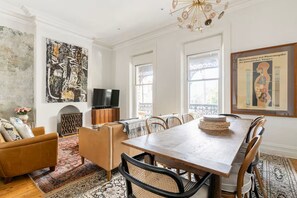 A dining area with a wooden table and chairs, a television, and artwork on the walls.