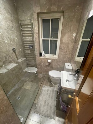 A bathroom with a shower, toilet, sink, and window.