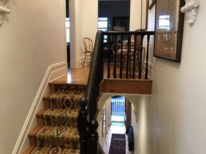 A staircase with patterned carpet leading to a dining area with wooden chairs and a table.