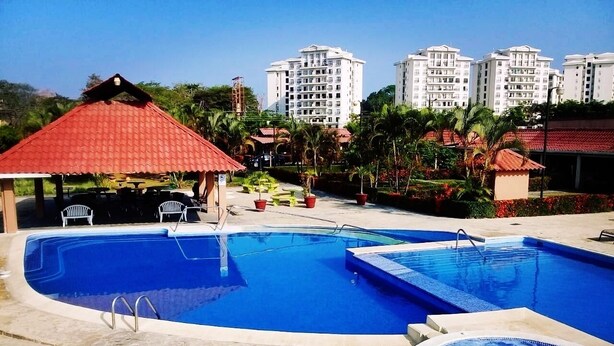 Una piscina con hidromasaje, sillas de descanso y un pabellón.