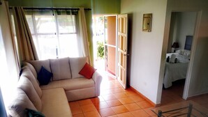Una sala de estar con un sofá, una mesa de comedor con sillas y una cama al fondo.