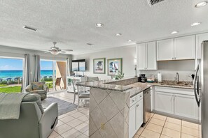 Une cuisine moderne avec vue sur l’océan, des meubles blancs et un coin repas offrant également une vue panoramique.